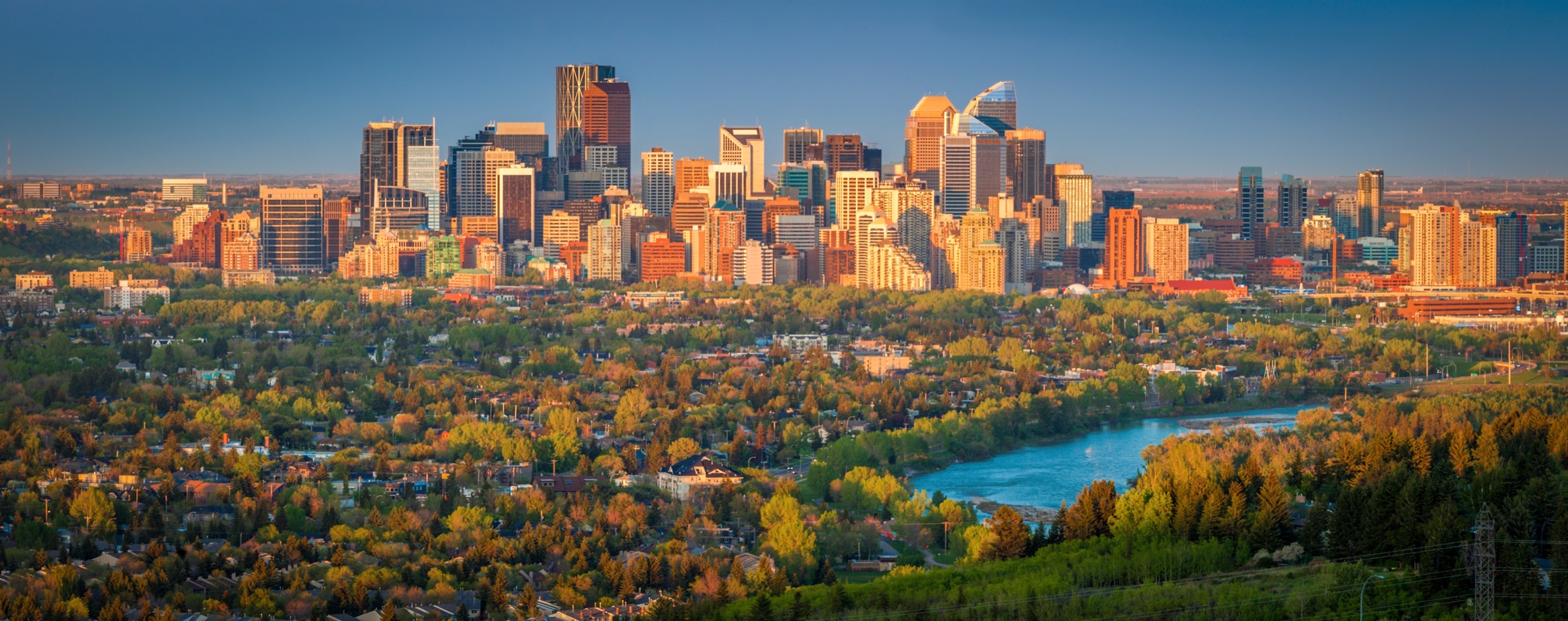 Calgary's downtown skyline at golden hour, with the Bow River in the foreground